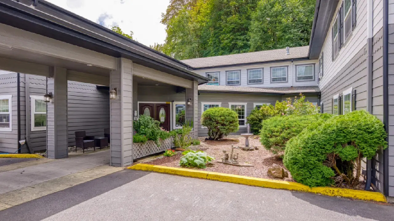 The front of a two-story building with a covered walkway and a landscaped garden with a birdbath The front of a two-story building with a covered walkway and a landscaped garden with a birdbath